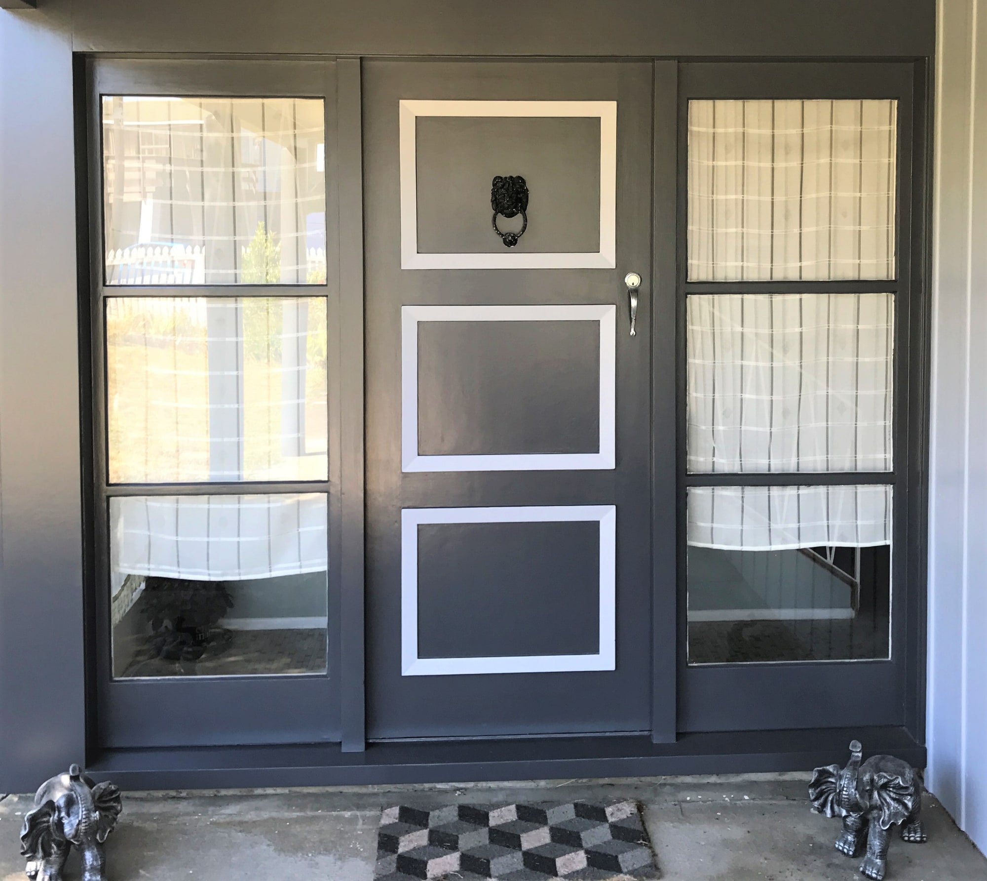 The same entry door repainted in charcoal with white panel detail and glazed sidelights.
