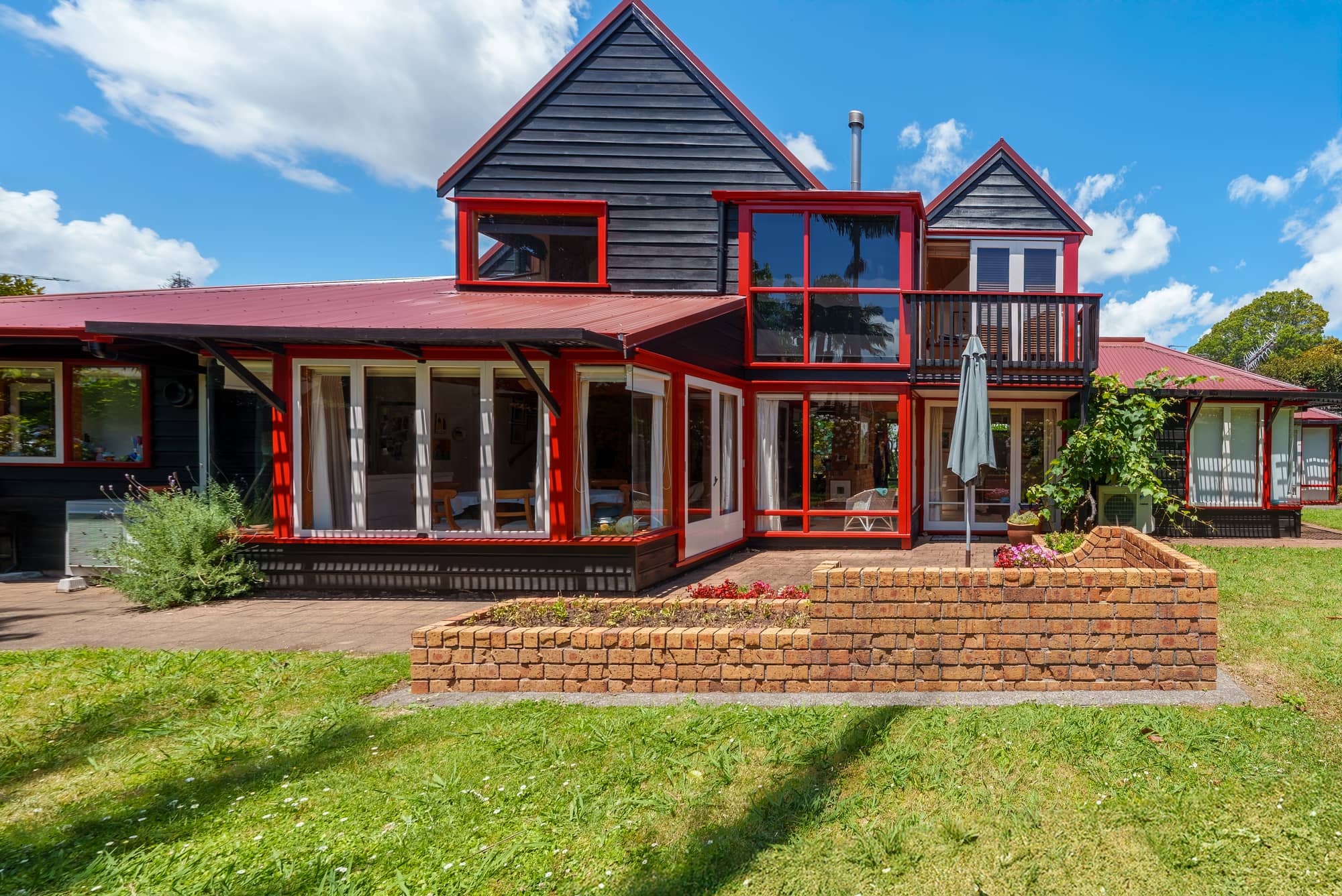 The full frontage of the house seen from the lawn, gables and verandah in view.