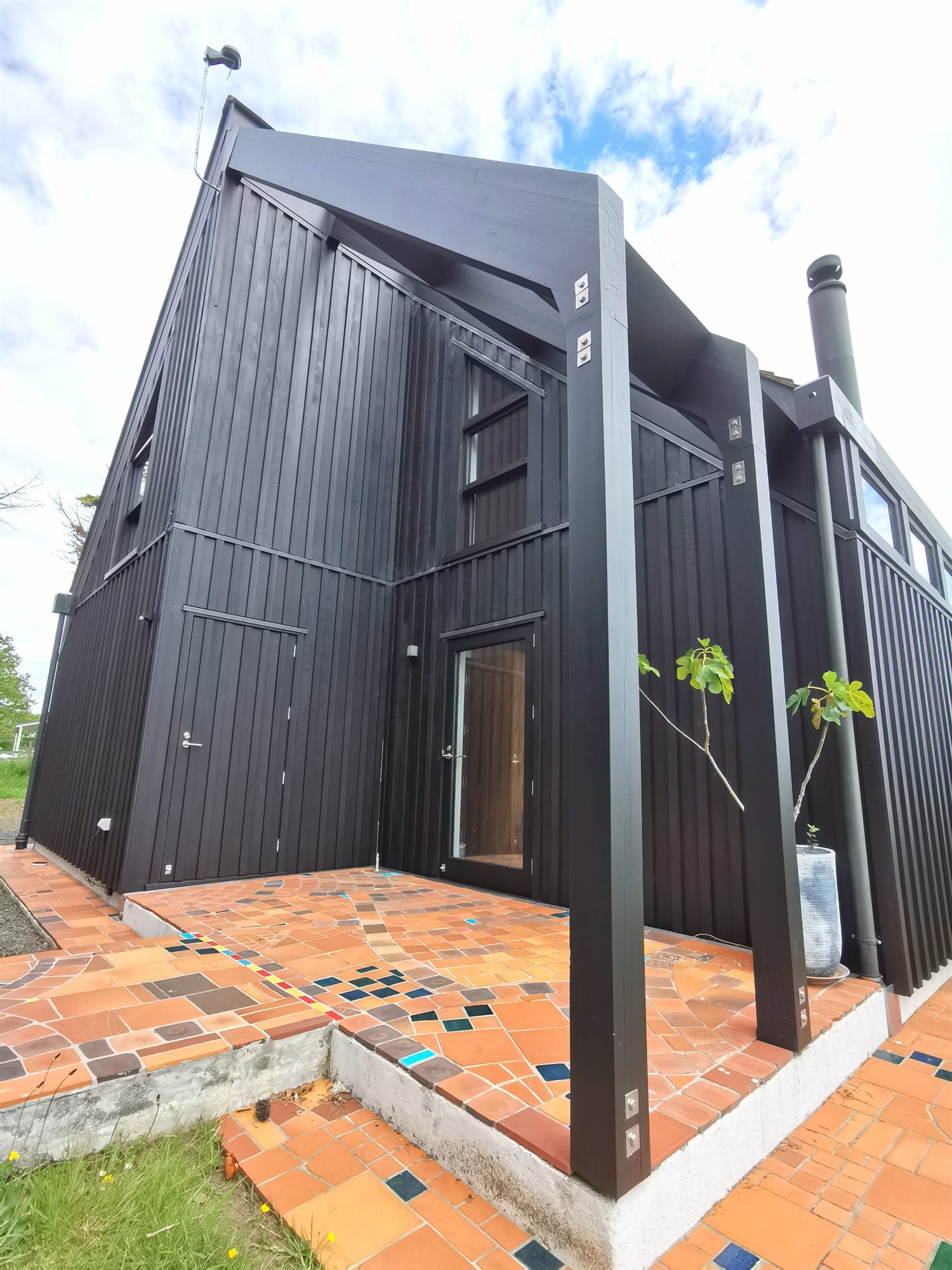 The studio entry under its raking roof, above a courtyard of patterned terracotta tiles.