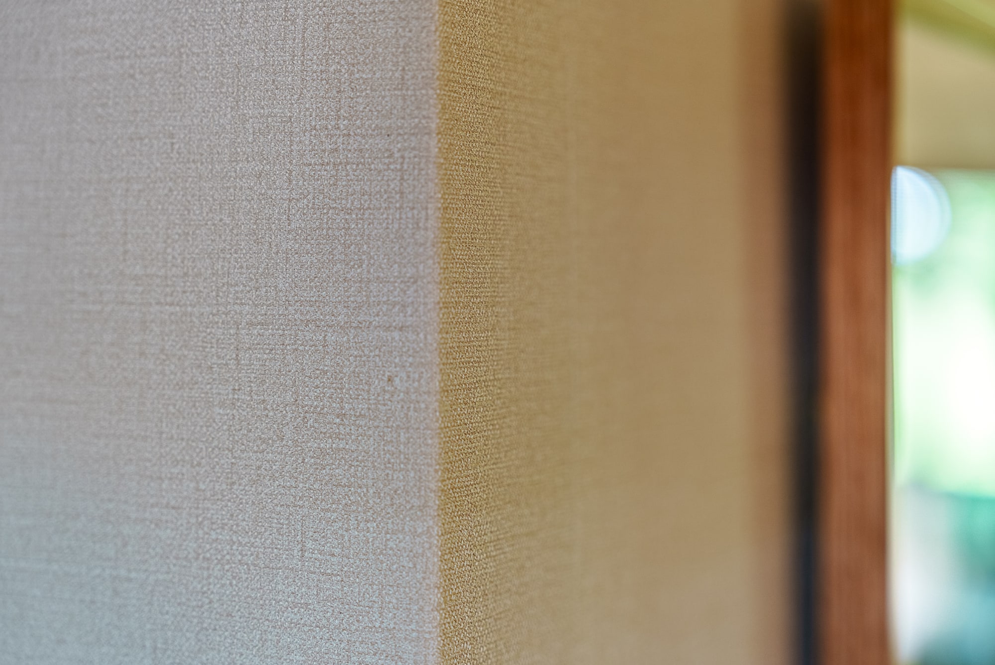 Close detail of a woven wallcovering meeting a gold panel.